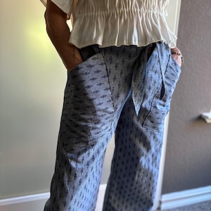 May include: Blue wide-leg pants with a diamond pattern and a white top with a ruffled hem.