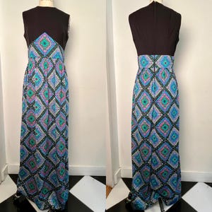 May include: A sleeveless black and patterned maxi dress. The bodice is black, transitioning to a patterned waist and skirt. The pattern features blue, green, and pink diamond shapes on a black background. The dress is displayed on a mannequin.