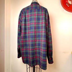 May include: A long-sleeved plaid shirt in a classic pattern. The shirt features a blue, green, and red plaid design. The shirt is displayed on a mannequin. The shirt is made of a soft, comfortable material.