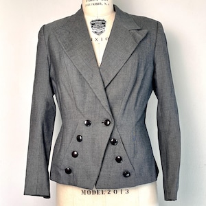 May include: A gray double-breasted blazer with six dark buttons. The tailored jacket features a notched lapel and a fitted silhouette. The blazer is displayed on a dress form.