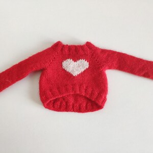 May include: A red knitted sweater with a white heart design.