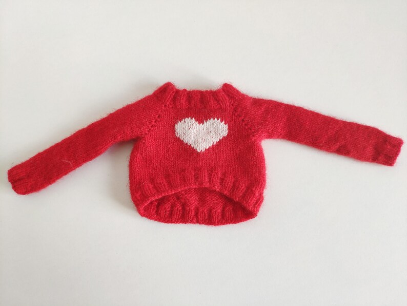 May include: A red knitted sweater with a white heart design.