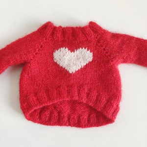 May include: Red knitted sweater with a white heart design.