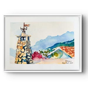 May include: Watercolour painting of a stone tower with a weather vane and a red flag. The artwork depicts a coastal scene with a red-tiled roof, mountains, and vibrant pink flowers. The painting is framed in a white border.