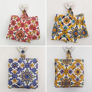 May include: Four sets of fabric potpourri sachets with a geometric tile pattern. The sachets are hung from a hook with a "Home Sweet Home" tag. The patterns include red, blue, yellow, and green.