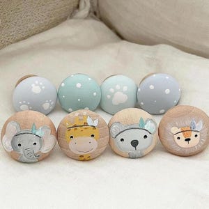 May include: Set of eight wooden knobs with painted animal faces and blue and white patterns. The animals include a giraffe, elephant, koala, and lion. The knobs are perfect for adding a whimsical touch to furniture or cabinets.
