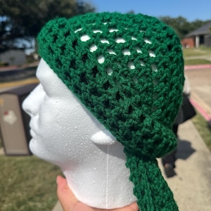 May include: A green crocheted hat with a long tail. The hat is made with a mesh pattern and has a loose fit.