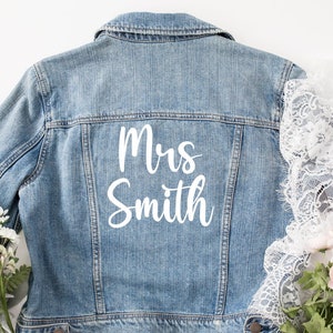 May include: A blue denim jacket with the text "Mrs. Smith" in white lettering on the back.