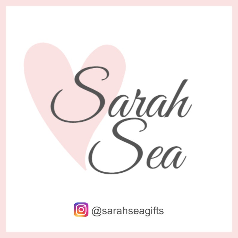 May include: A pink heart with the text "Sarah Sea" in gray cursive lettering. The text "@sarahseagifts" is below the heart in gray lettering.