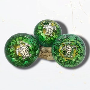 May include: Three green resin paperweights with a silver turtle design. Each paperweight has a different pattern of green and gold speckles.