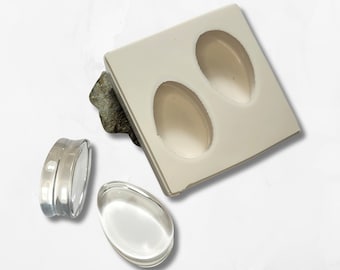 May include: A white silicone mold with two oval-shaped cavities. Two clear resin pieces are shown next to the mold.