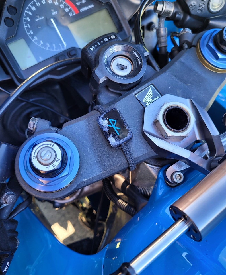 May include: Close-up of a blue motorcycle with a black ignition key, a black and blue handlebar, and a silver Honda logo. The motorcycle has a black and blue handlebar with a black and blue ignition key. The motorcycle has a silver Honda logo on the side.