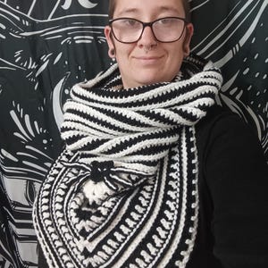 May include: A black and white striped crocheted scarf with a geometric pattern. The scarf has a tassel at the bottom.