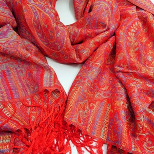 Peut inclure: Une écharpe rouge à motif paisley avec une bordure frangée. L'écharpe est faite d'un tissu doux et léger, parfait pour ajouter une touche de couleur et de style à n'importe quelle tenue.