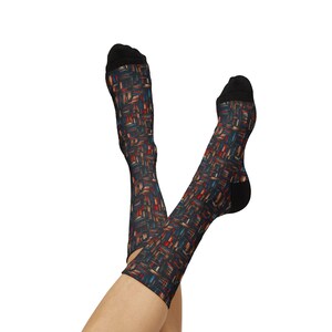 May include: A pair of knee-high socks with a colorful, abstract pattern. The socks feature a black toe and heel, and the design incorporates red, blue, and gold rectangular shapes on a dark background. The socks are displayed with the legs crossed.