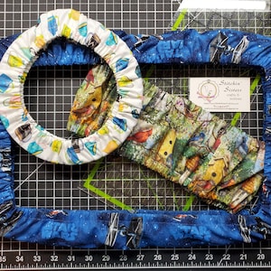 May include: Three fabric covers for a round pot, a rectangular pan, and a square pan. The covers are made of white fabric with a blue and yellow pattern, green fabric with a birdhouse and bird pattern, and blue fabric with a Star Wars pattern. The text "Stitch'n Sisters crafts & notions" is visible on a white card.