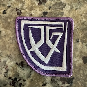 May include: Purple embroidered patch with a white stylized letter "D" inside a white square.