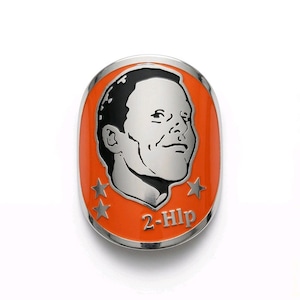 May include: An oval-shaped metal pin featuring a silver-toned portrait of a person against a vibrant orange background. The design includes three silver stars and the text 2-Hlp embossed in silver, all framed by a polished silver-toned metal border.