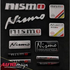 Könnte beinhalten: Eine Sammlung von Nismo-Autoemblemen in verschiedenen Formen und Größen. Die Embleme zeigen das Nismo-Logo in Weiß, Rot und Schwarz. Einige enthalten den Text "NISSAN MOTORSPORTS INTERNATIONAL". Der Hintergrund ist schwarz.