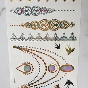 May include: Gold and black temporary tattoo sheet with a variety of designs, including a necklace, bracelets, and birds. The sheet also includes the text "YHH-005".
