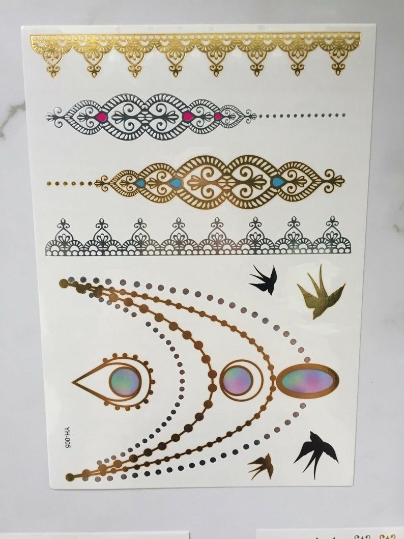 May include: Gold and black temporary tattoo sheet with a variety of designs, including a necklace, bracelets, and birds. The sheet also includes the text "YHH-005".