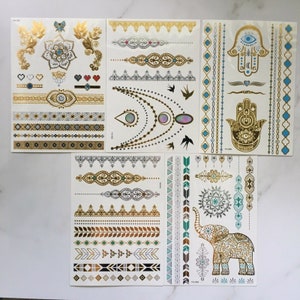 May include: Set of gold and turquoise temporary tattoos with various designs including a hamsa hand, an elephant, and geometric patterns.