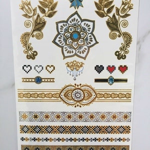 May include: Gold and silver temporary tattoo sheet with a variety of designs, including a flower, a bow, hearts, and geometric patterns. The sheet is labeled "YH-002".