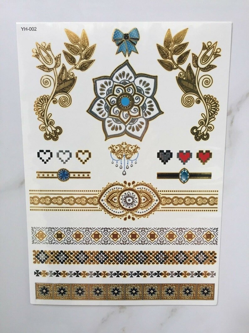 May include: Gold and silver temporary tattoo sheet with a variety of designs, including a flower, a bow, hearts, and geometric patterns. The sheet is labeled "YH-002".