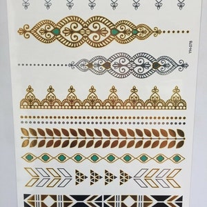 May include: A sheet of temporary tattoos with a variety of gold, silver, and black designs. The designs include geometric patterns, floral motifs, and arrows. The sheet is labeled "YH-078".