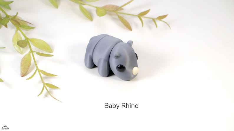 May include: A small, gray, clay sculpture of a baby rhinoceros. The rhino has a small, white horn and black eyes.