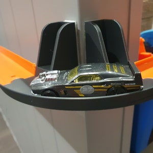 May include: A black toy car with a gold stripe and the text "Metron 6" on the side. The car is on a black and orange toy track.