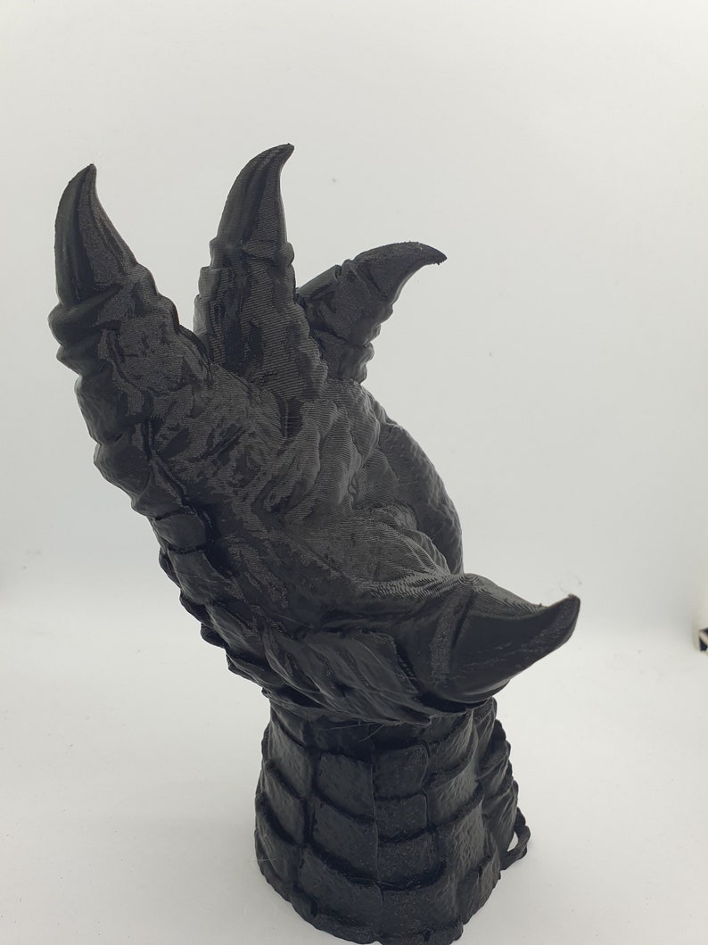 May include: A black 3D printed dragon claw sculpture with sharp, detailed claws and a textured wrist.