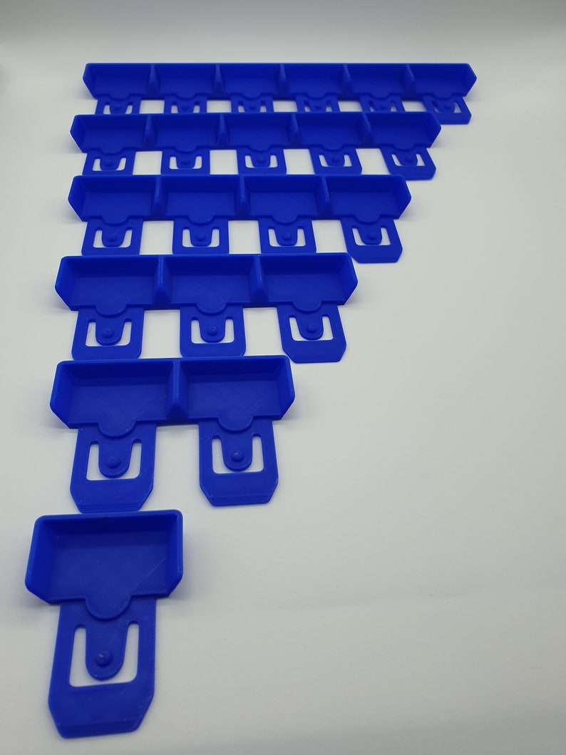 May include: Arrangement of blue plastic components, each with a rectangular tray and a U-shaped clip. The components are stacked in a descending order, creating a stepped pattern. The objects are on a white background.