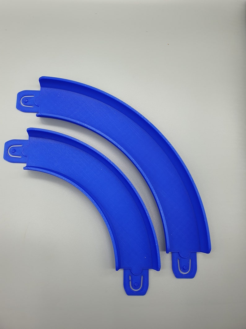 May include: Two blue plastic track pieces for a toy race car track. The pieces are curved and connect together.
