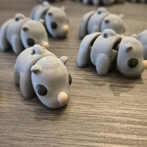 K&ouml;nnte beinhalten: Eine Sammlung von grauen, artikulierten, 3D-gedruckten Tierfiguren. Die Figuren haben die Form eines Nashorns mit einem runden K&ouml;rper und einem kleinen Horn auf der Nase. Die Figuren haben schwarze Augen und eine wei&szlig;e Nase.