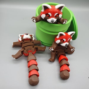 May include: Two red panda figurines with articulated limbs and a segmented tail. One red panda is inside a green cylindrical container with a lid.
