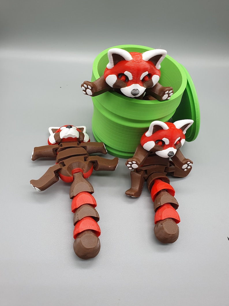 May include: Two red panda figurines with articulated limbs and a segmented tail. One red panda is inside a green cylindrical container with a lid.