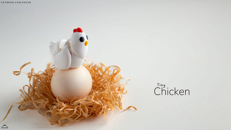 May include: A small white chicken figurine with red and black details sits on top of a white egg in a nest of straw. The text "Tiny Chicken" is written below the nest.