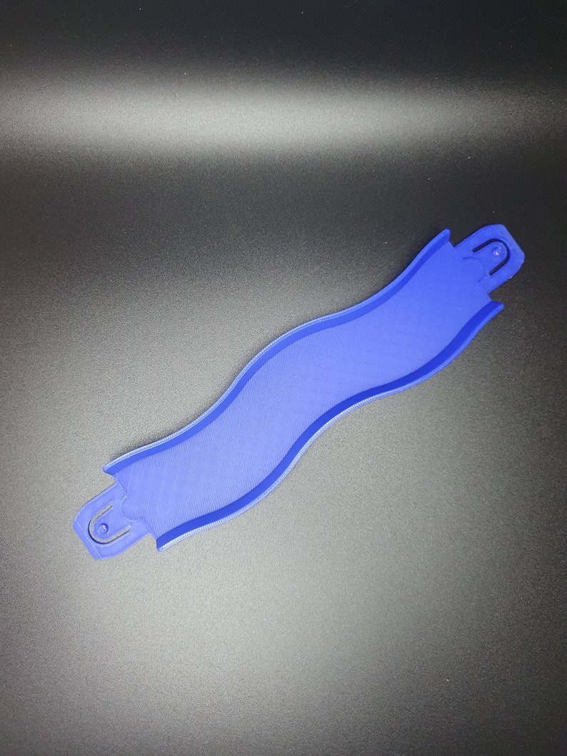 May include: A blue plastic track piece for a toy race car track. The piece is curved and has a textured surface.
