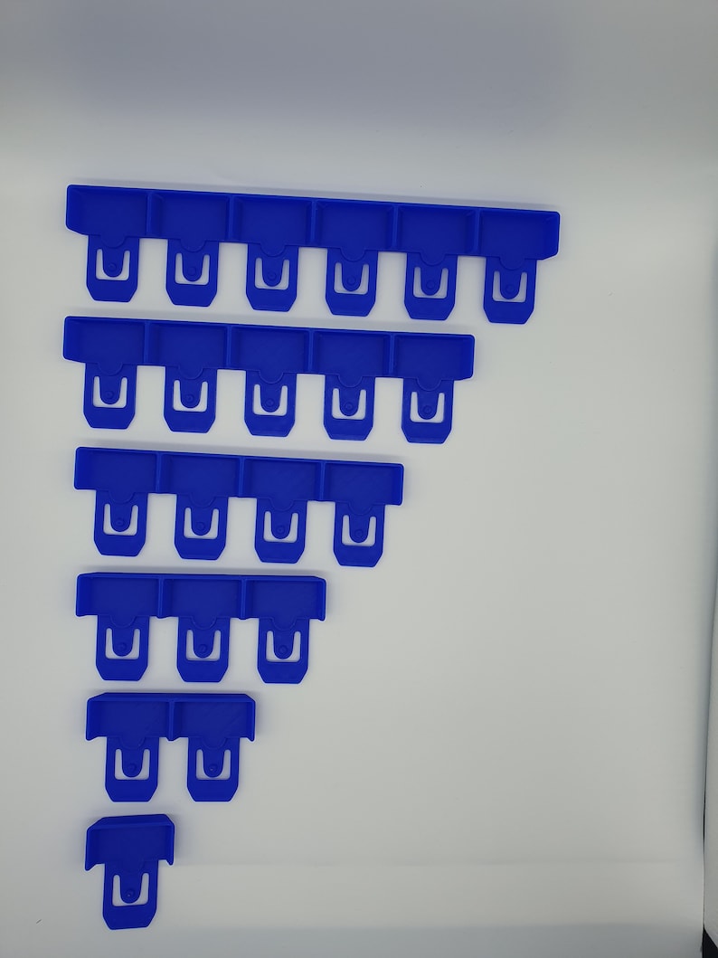 May include: A collection of blue plastic clips arranged in a descending staircase pattern. Each clip has a rectangular top with a U-shaped opening. The clips are a vibrant shade of blue and appear to be new.