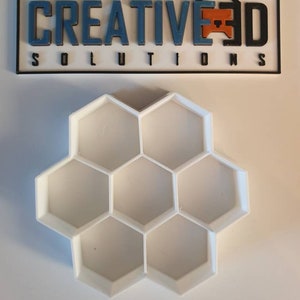 May include: White plastic honeycomb-shaped mold with six hexagonal compartments.