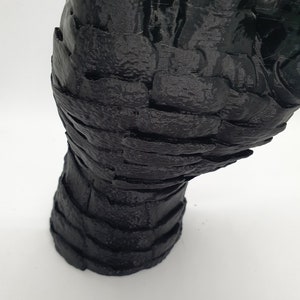May include: A black 3D printed hand sculpture with a textured surface.