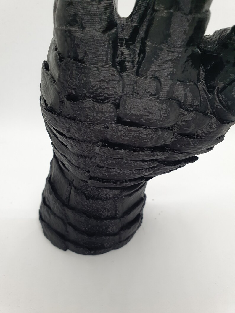 May include: A black 3D printed hand sculpture with a textured surface.