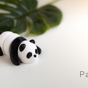 PandaTwirl™ Baby Panda Fidget Keyring: "A miniature, hand-painted panda keychain, featuring a baby panda in a sitting position. The panda has big, round eyes, a soft white and black color scheme, and a smooth surface.