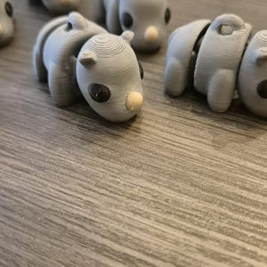 K&ouml;nnte beinhalten: Eine Sammlung von grauen, 3D-gedruckten Nashorn-Figuren. Die Figuren sind klein und haben schwarze Augen und ein wei&szlig;es Horn.