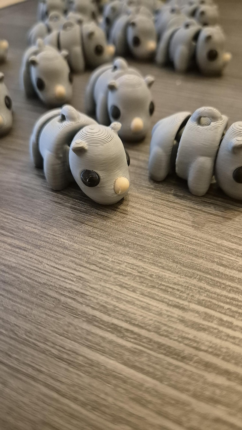 K&ouml;nnte beinhalten: Eine Sammlung von grauen, 3D-gedruckten Nashorn-Figuren. Die Figuren sind klein und haben schwarze Augen und ein wei&szlig;es Horn.