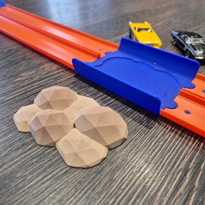 Puede incluir: Un conjunto de formaciones rocosas geom&eacute;tricas marrones impresas en 3D para una pista de carreras de juguetes. Las rocas est&aacute;n dispuestas en un grupo y est&aacute;n hechas de un material texturizado.
