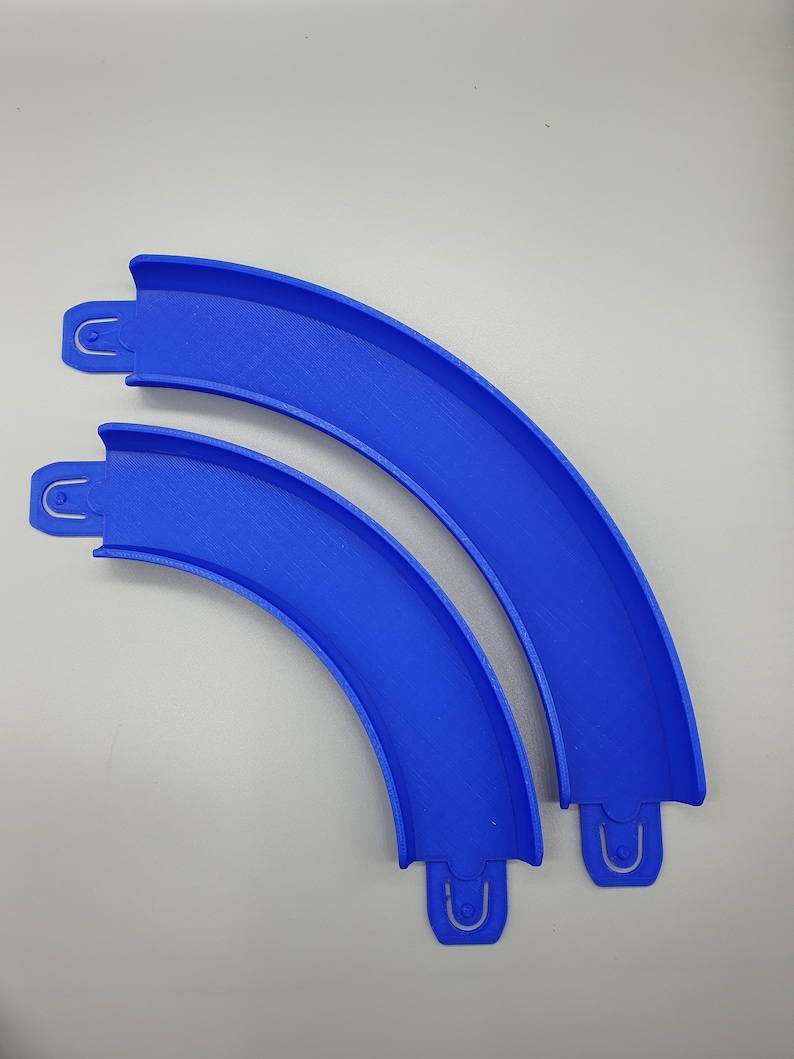 May include: Two blue plastic track pieces for a toy race car track. The pieces are curved and connect together to form a track.