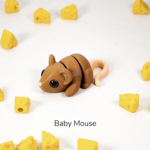 Puede incluir: Un juguete de rat&oacute;n beb&eacute; marr&oacute;n con una cola enroscada rodeado de bloques de queso amarillo. El texto "Baby Mouse" est&aacute; escrito debajo del juguete.
