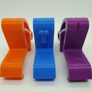 May include: Three 3D printed door stops in orange, blue, and purple. Each door stop has a different design. The orange door stop has the word "CAUTION" printed on it. The blue door stop has a small, raised, phallic symbol. The purple door stop has the words "Get a Life" printed on it.